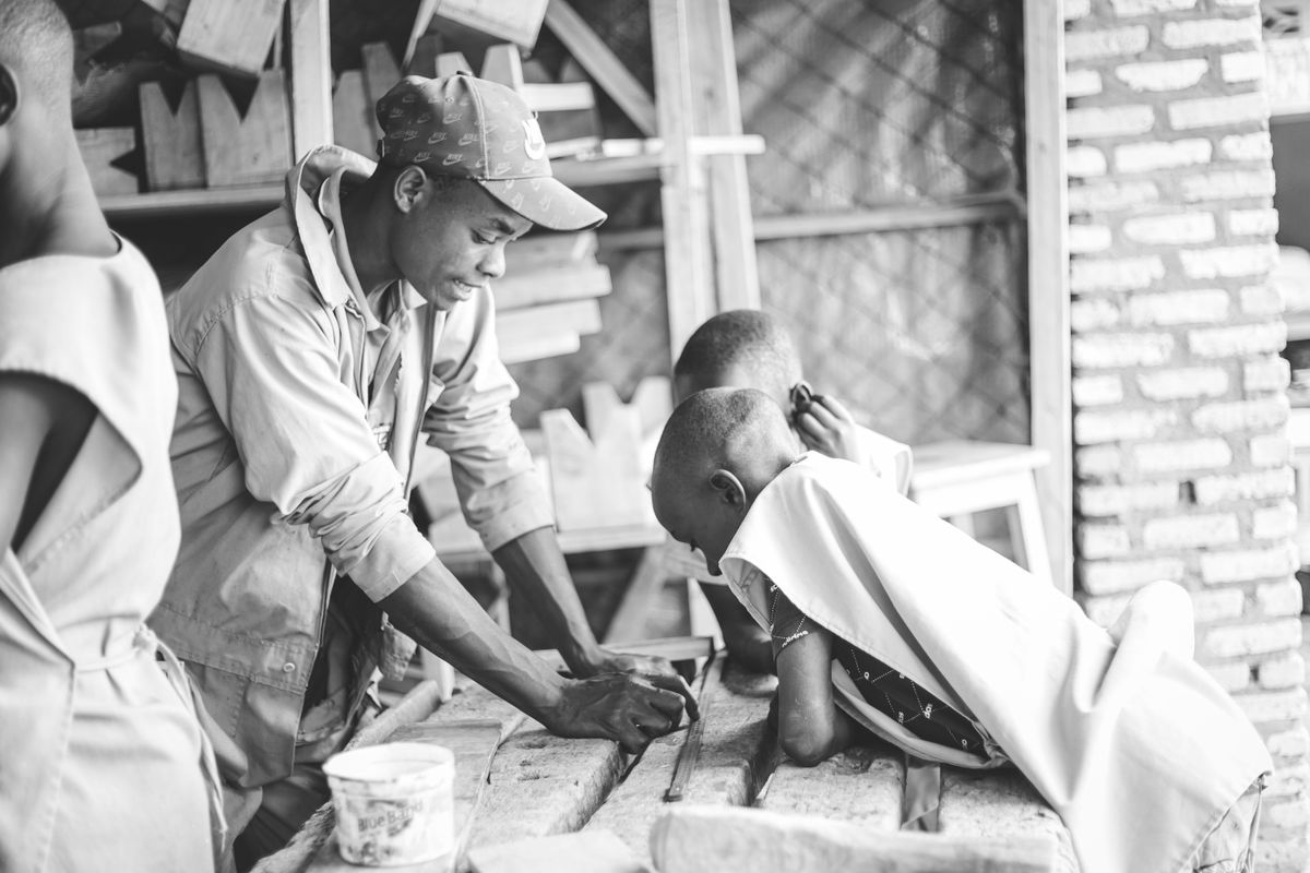 Mentor guiding children in a practical vocational-training activity